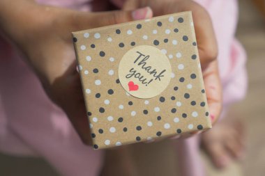  Hediye kutusuna bir teşekkür etiketi yapıştırıyorum. .