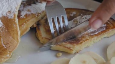 Tabakta muz ile servis edilen bıçakla keki kesmeye yakın plan. ,