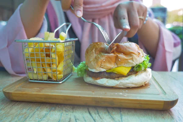 women eating Cheeseburger served with fries on table ,