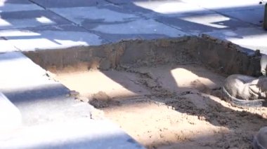 İşçiler yol kenarındaki çukura atmak için taşları kürekle alır. ,