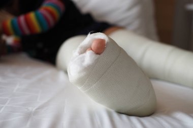 Bacağında yara bandı olan küçük bir çocuk.