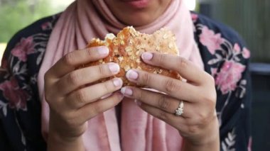 Kadınlar ellerinde et burgeri tutuyor. .
