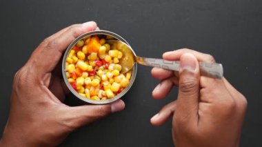 kaşık konserve kutusundan tatlı mısır topluyor. ,