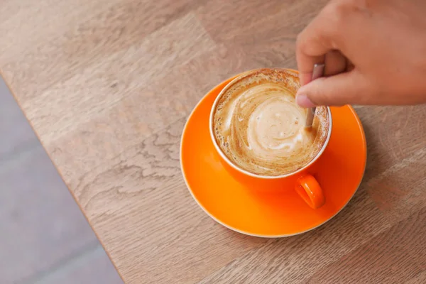 person hand stirring coffee with spoon