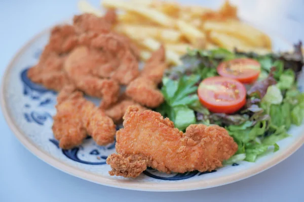 fried chicken fillets served with salad and french fries .