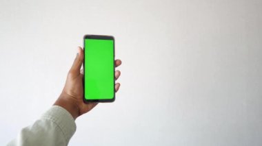 Genç adam yeşil ekranlı akıllı telefon kullanıyor. .