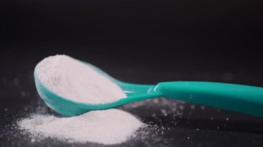 Siyah arka planda bebek sütü tozu ve kaşığı kapat..