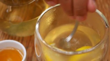  Elde kaşık, masada ballı limon çayı karıştırıyor. .
