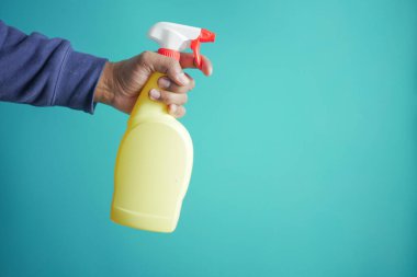 holding a plastic bottle spraying disinfect .