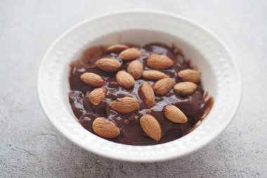 Koyu çikolatalı krema beyaza badem fıstığı döküyor. .