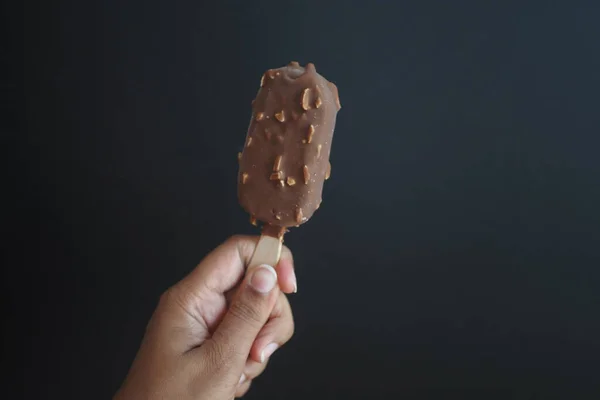 stock image  person hand holding ice cream against black background ,