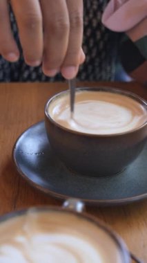 İnsan, kaşıkla kahve karıştırır.