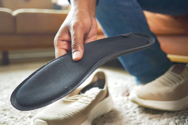 men hand putting Orthopedic insoles in shoes .