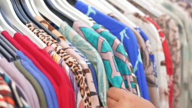 Kadın dükkanda kıyafet seçiyor.