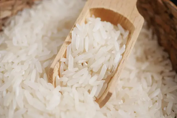 Raw white rice on a wooden spoon .