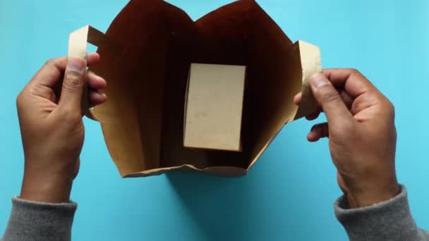 男人从牛皮纸购物袋里拿出一个盒子 — 图库视频影像
