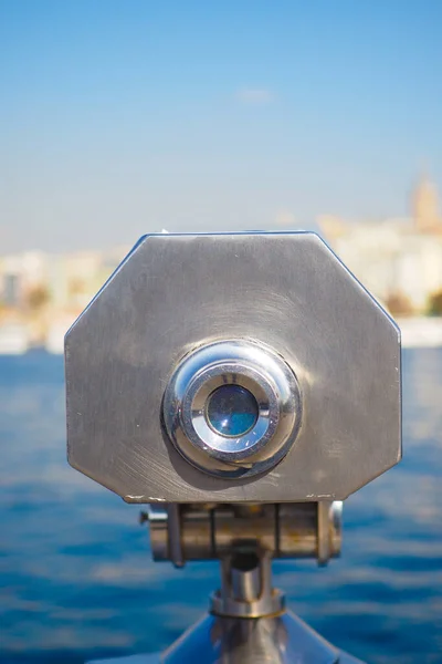 Coin-operated binoculars looking out over city buildings