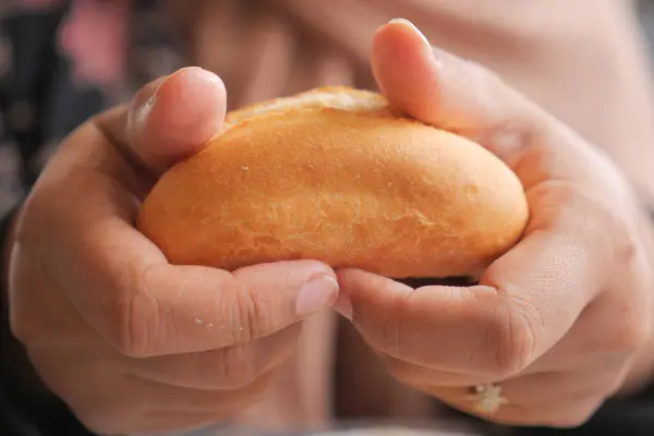 women hand pick baked bun on table .