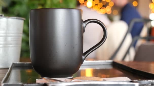 カフェの背景にあるテーブルの上の黒い色のコーヒー マグカップのモックアップ — ストック動画