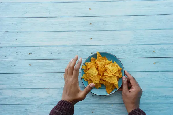 men hand pick potato chips from a plate .