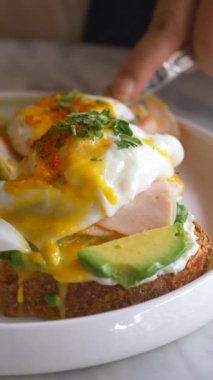 Yumurtalı, jambonlu ve avokadolu bir tabağı tostun üzerine koy. .