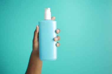 Adamın elinde plastik bir losyon şişesi var..