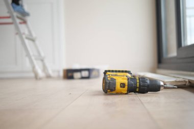 Yerde elektrikli bir tornavida var.