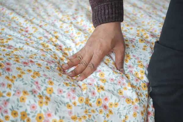 Hand touching and pressing orthopedic mattress on bed