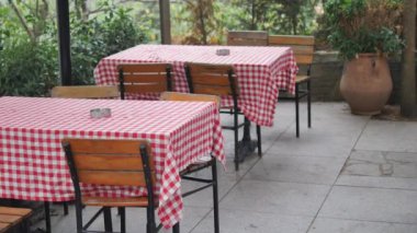 Dışarıdaki ahşap masa ve kırmızı masa örtülü sandalyeler. .