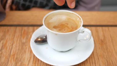 Kahve fincanına küp şeker düşürmek. 