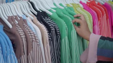 Kadın dükkanda kıyafet seçiyor.