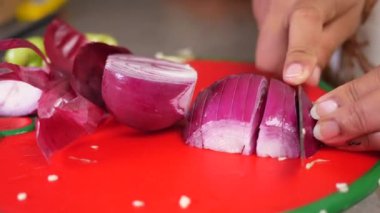 Kadınlar kırmızı soğanı doğrama tahtasına elleriyle keserler. .