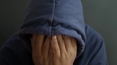 Kapüşonlu üzgün adam elleri siyah kaplı.