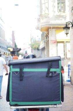 Motosikletli, sırtında büyük bir çanta olan, asfalt üzerinde seyahat eden biri.,