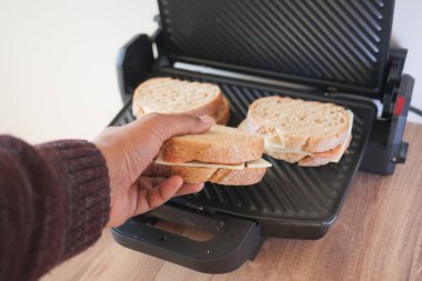 Birisi ızgaradan ızgara sandviç alıyor..