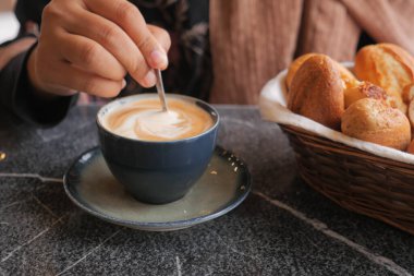 İnsan, kaşıkla kahve karıştırır.