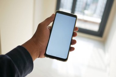 Boş odada beyaz ekranı gösteren telefon kullanan el pov 'u.