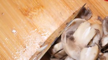 Taze şampiyon mantarını doğrama tahtasının üstünde kesmenin en üst görüntüsü .