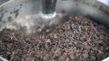 Taze içecek için metal kasede öğütülmüş siyah çay yaprakları..