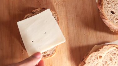 Ekmeğe peynir ve sosis koyan biri. .