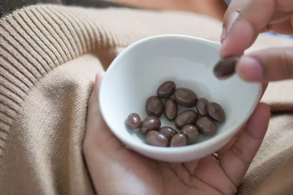 woman hand pick round shape chocolate candy in a bowl .