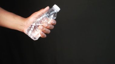 Bir insan parmakları ve başparmağıyla plastik bir şişeyi kavrıyor..