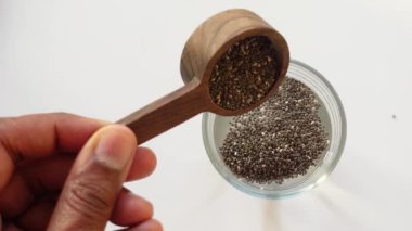 Chia tohumlarının üst görüntüsü bir bardak suya dökülüyor. .