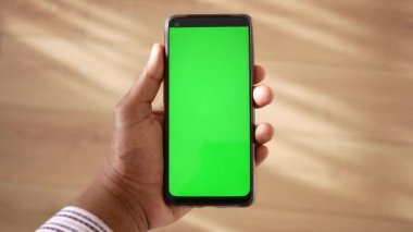 Evde yeşil ekranlı akıllı telefonu tutmanın POV görüntüsü .