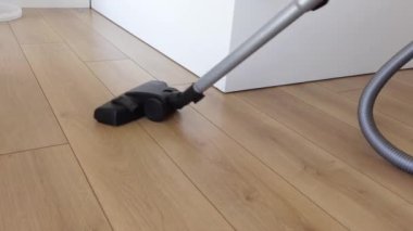 Kadın yer tozunu elektrikli süpürgeyle temizliyor.