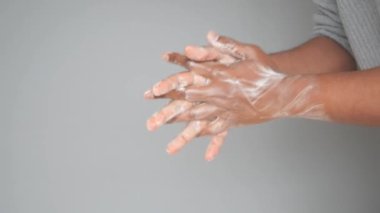 Genç adam ellerini sabunla sıcak suyla yıkıyor..