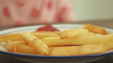 Küçük bir kız patates kızartması topluyor. .