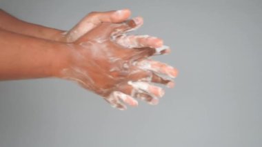 Genç adam ellerini sabunla sıcak suyla yıkıyor..