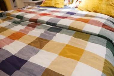 Mor, Turuncu ve Sarı tonlarında yastıkları olan renkli bir yatak.