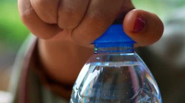 Plastik bir su şişesinin kapağını aç. .